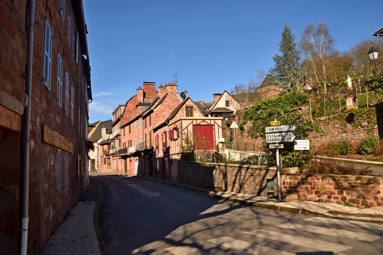 Rue du village de Villecomtal en Aveyron, maisons en grès rouge et pans de bois